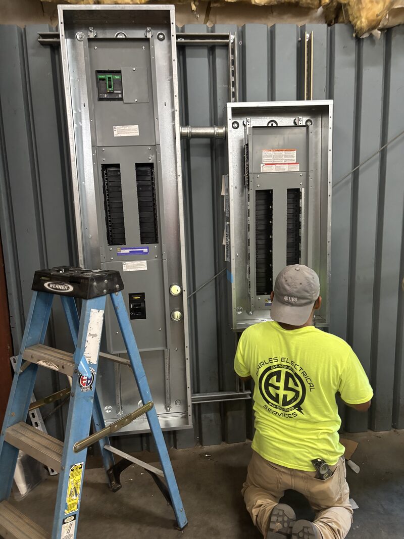 Quarles electrician in a branded shirt servicing large commercial electrical panelboards