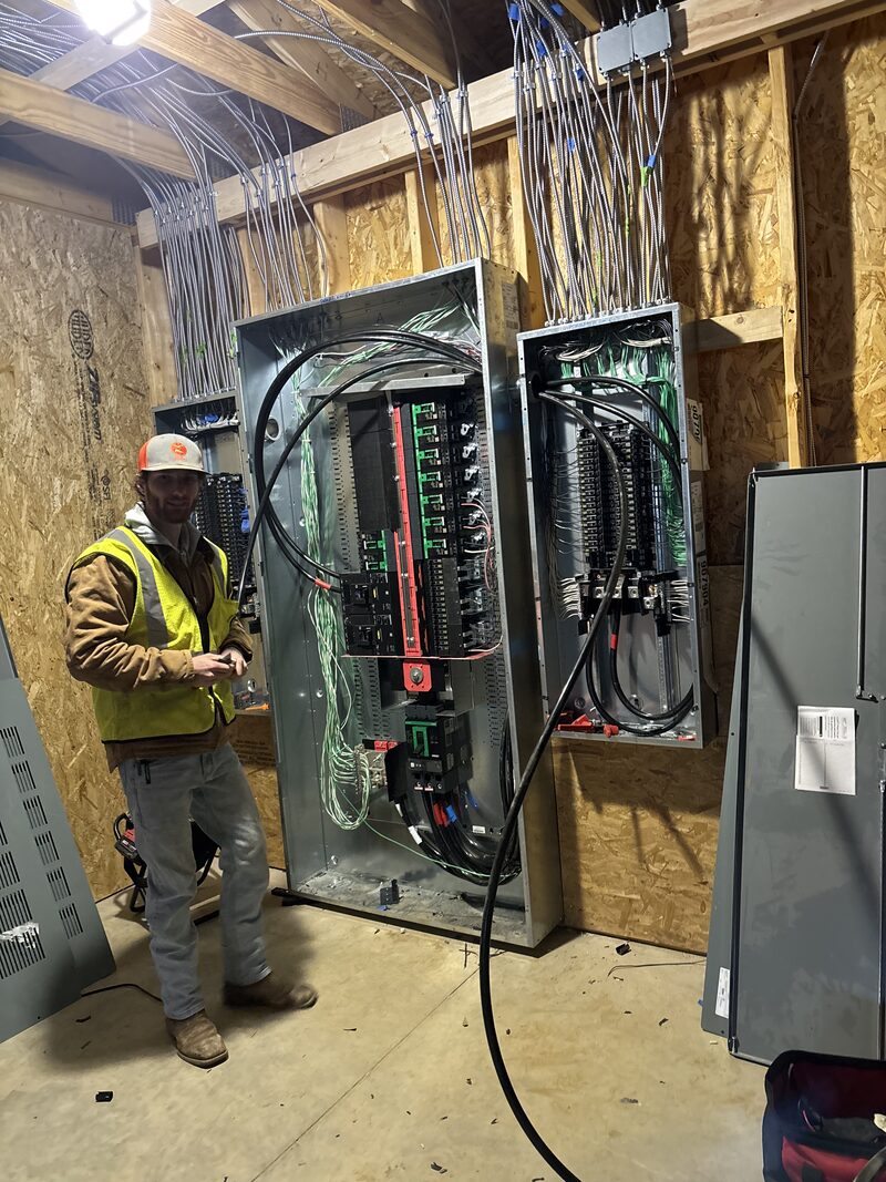 Electrician at new-construction electrical panels with bundled circuit wiring